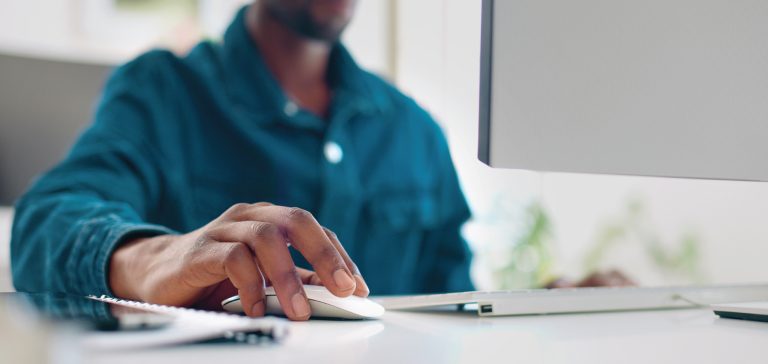 man at his desk using his mouse on his desktop computer